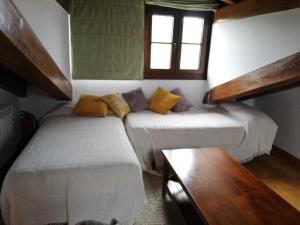 Cette chambre comprend 2 lits, une table et une fenêtre. dans l'établissement Apartamento Peña Sol B (Bustio), à Bustio