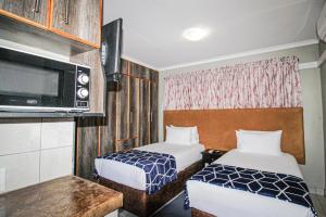 Kleines Zimmer mit 2 Betten und einer Mikrowelle in der Unterkunft PW Heights Private Guest House in Thohoyandou