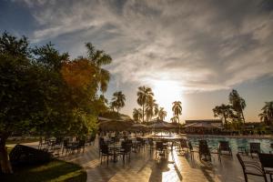 a pool with chairs and tables and the sun setting at Grand Carimã Resort & Convention Center in Foz do Iguaçu