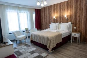 a hotel room with a large bed and a chair at Pensiunea Carmen`s Mansion B in Sinaia