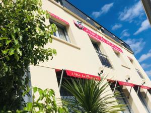 a view of the side of a building with a red awning at Hôtel de Matignon Restaurant Le EmLo in Matignon