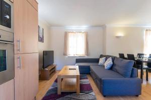 a living room with a blue couch and a table at Godwin Court Apartments in Swindon