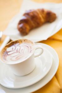 una tazza di caffè e un prodotto da forno su un tavolo di Hotel Candido a Diano Marina