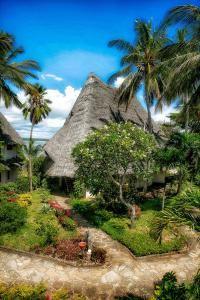 a thatch roofed house with palm trees and flowers at Temple Point Resort in Watamu