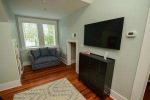 a living room with a flat screen tv and a chair at 607 Bay Inn Downtown Beaufort in Beaufort