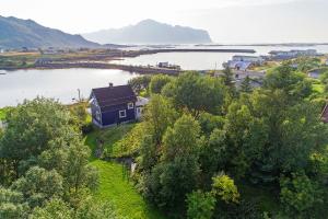 a house on a hill next to a lake at Fishermans Village Lofoten in Alstad