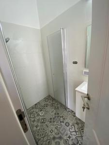 a small bathroom with a shower and a tiled floor at יחידת נופש בבית ורדי in Tiberias