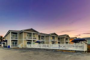 a row of apartment buildings with a white fence at Palm Suites in Atlantic Beach