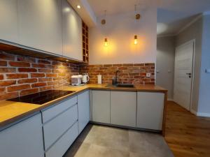 uma cozinha com armários brancos e uma parede de tijolos em Bastion Apartment Gdansk City Center em Gdansk