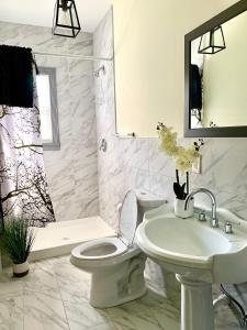 a white bathroom with a toilet and a sink at The Iron Scow - With Private Yard & Free Parking, Minutes From Falls & Casino by Niagara Hospitality in Niagara Falls