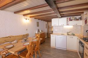 uma cozinha com uma mesa de madeira e uma cozinha com electrodomésticos brancos em Résidence Les hauts de Val Cenis em Lanslevillard