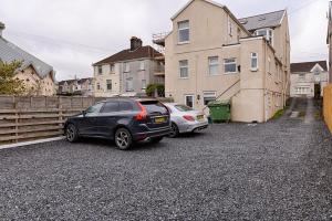 twee auto's geparkeerd op een oprit voor een huis bij Alexandra Lodge in Swansea