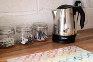 a coffee maker sitting on a counter with jars and a cutting board at Alexandra Cottage Comfortable Apt near Swansea & M4 in Swansea +9 photos
