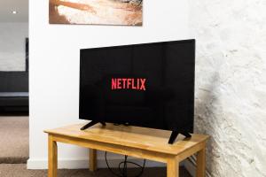 a television on a wooden table in front of a wall at Alexandra Cottage Comfortable Apt near Swansea & M4 in Swansea
