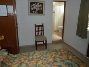 a bedroom with a bed and a chair and a toilet at Hotel Bajo el Volcan in Cuernavaca