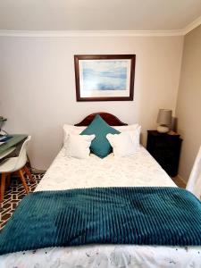 a bedroom with a bed with a green blanket on it at Mountain Rose Cottage in Bellville