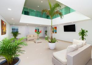 un vestíbulo con muebles blancos y palmeras en Playa Norte Hotel en Cartagena de Indias