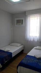 two beds in a small room with a window at Flat Espinheiro Prime in Recife