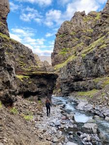a person walking through a river in a canyon at Hlín Guesthouse in Varmahlid
