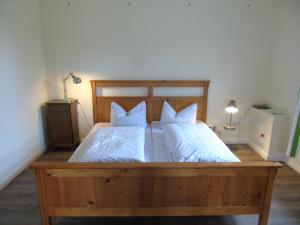 ein Schlafzimmer mit einem großen Holzbett mit zwei Kissen in der Unterkunft Futterhaus neben der Wasserburg Liepen in Gielow