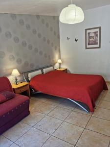 a bedroom with a red bed and a couch at La Chaumiere in Agde