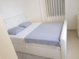 a white bed with blue sheets and pillows on it at Diar Apartment in Durrës