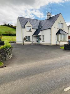 a large white house with a large driveway at Cloneymore Self Catering House in Cushendun
