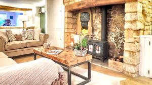 a living room with a stone fireplace and a table at Magnolia Cottage in Moreton in Marsh