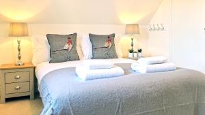 a bedroom with a bed with four pillows at Magnolia Cottage in Moreton in Marsh