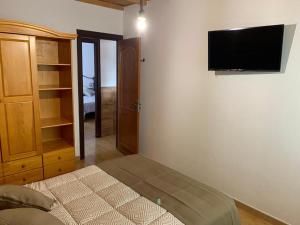 - une chambre avec un lit et une télévision murale dans l'établissement Casa Juani, à Las Palmas de Gran Canaria