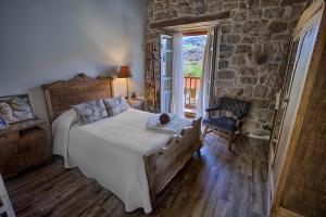 - une chambre avec un grand lit et un mur en pierre dans l'établissement La Curva De María, à Terán