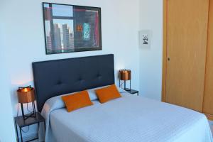 ベニドルムにあるApartamento de Lujo con terraza privada y vistas al mar en Torre Lúganoのベッドルーム1室(オレンジ色の枕2つ、ベッド1台付)