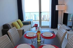 a living room with a table with plates and wine glasses at Skyline 20 Apartamento de Lujo con terraza privada y vistas al mar in Benidorm