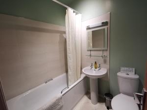 a bathroom with a sink and a toilet and a bath tub at Kings Arms Holiday Apartments in Oban