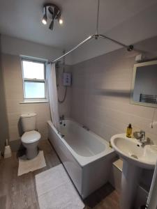 a bathroom with a tub and a toilet and a sink at Kings Arms Holiday Apartments in Oban