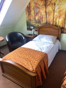 een slaapkamer met een bed en een stoel en een schilderij bij Nagybajcsi Lovaspark és Otthon vendégház in Nagybajcs