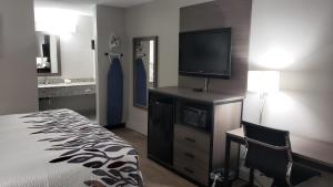 ein Hotelzimmer mit einem Bett und einem Flachbild-TV in der Unterkunft Red Roof Inn Cullman in Cullman