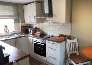 een keuken met witte kasten en een fornuis met oven bij The Saddlery Holiday Cottage - Near Wolds And Coast in North Thoresby