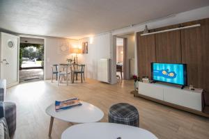 uma sala de estar com uma televisão e uma mesa e cadeiras em Complex Lagonissi Residence with swimming pool. em Lagonissi