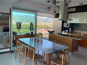 een keuken met een tafel met stoelen en een groot raam bij PENINSULA VALLARTA , Departamentos Piso 8 y 10 hacia el Mar in Puerto Vallarta