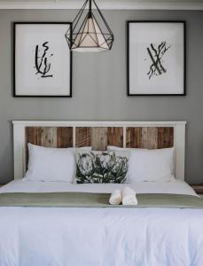 een slaapkamer met een wit bed met drie foto's aan de muur bij The Living Collective Villa in Hilton