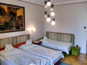 2 camas en una habitación de hotel con sábanas blancas en Cola Panzió, en Szentendre