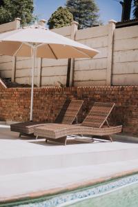 twee stoelen en een parasol naast een zwembad bij The Living Collective Villa in Hilton