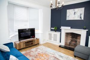 a living room with a tv and a fireplace at Porchester House Nottingham in Nottingham