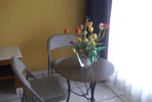 una mesa y sillas con un jarrón de flores. en Hotel Arcos Aeropuerto, en Veracruz