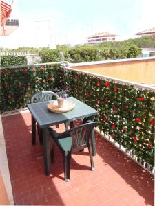 un tavolo e due sedie su un patio con rose rosse di Apartments Porto Santa Margherita 40282 a Porto Santa Margherita di Caorle
