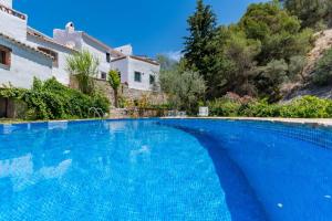 duży niebieski basen z domem w tle w obiekcie Casa Rosa, con encanto y piscina climatizada w mieście Frigiliana +18 zdjęć