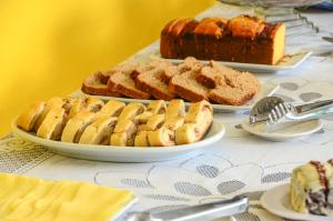 une table recouverte de assiettes de pain et de desserts dans l'établissement Pousada Primavera, à Parati
