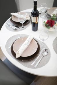 a white table with a plate and a bottle of wine at Primadonna Apartments in Šibenik