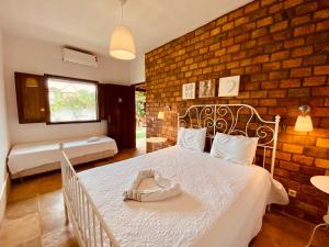 um quarto com uma cama branca e uma parede de tijolos em Casa Dos Patos em Flecheiras